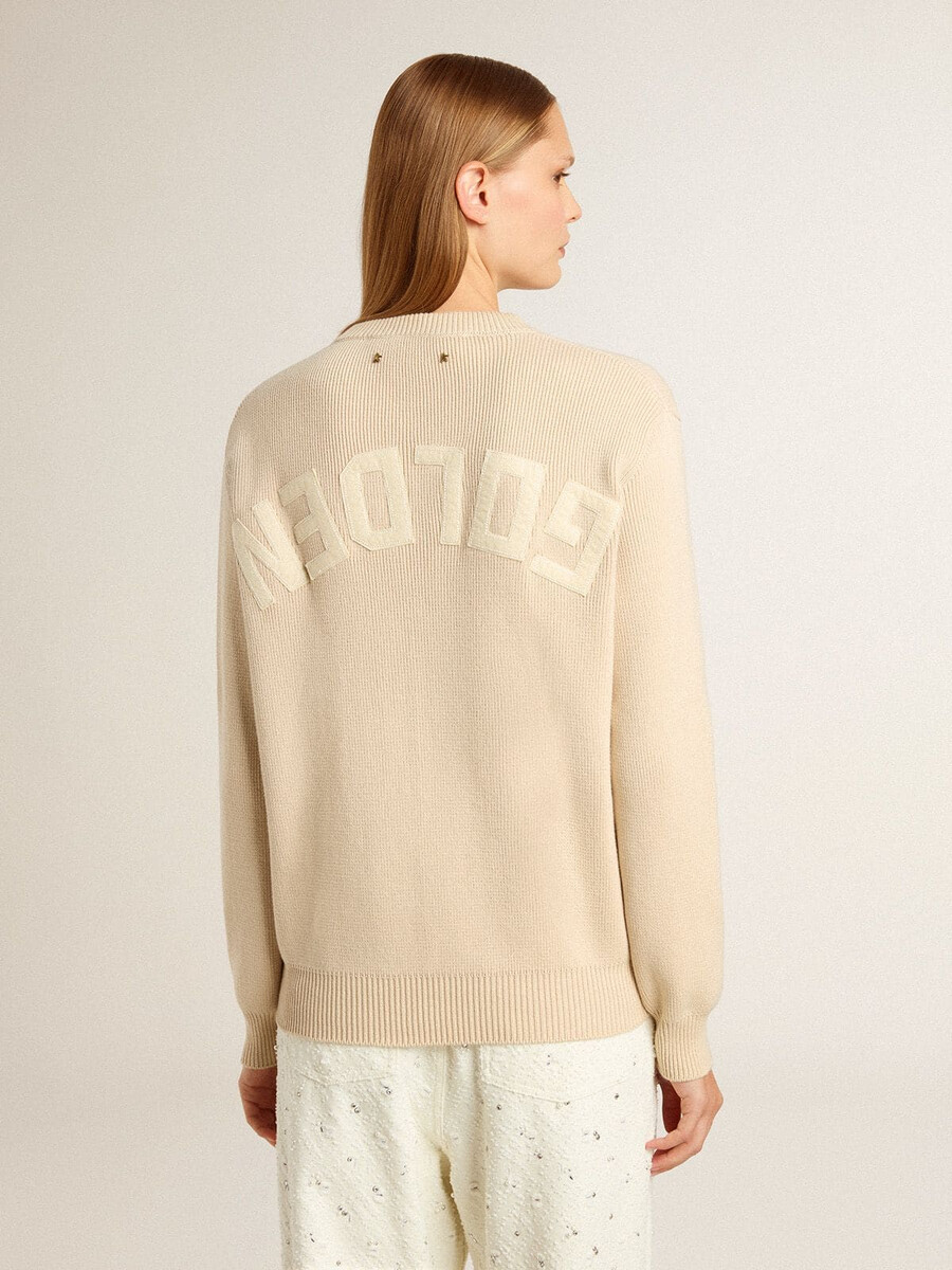 beigefarbener damenpullover mit dem schriftzug „golden auf dem rücken