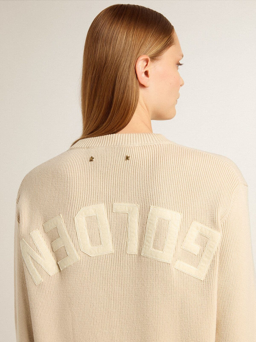 beigefarbener damenpullover mit dem schriftzug „golden auf dem rücken