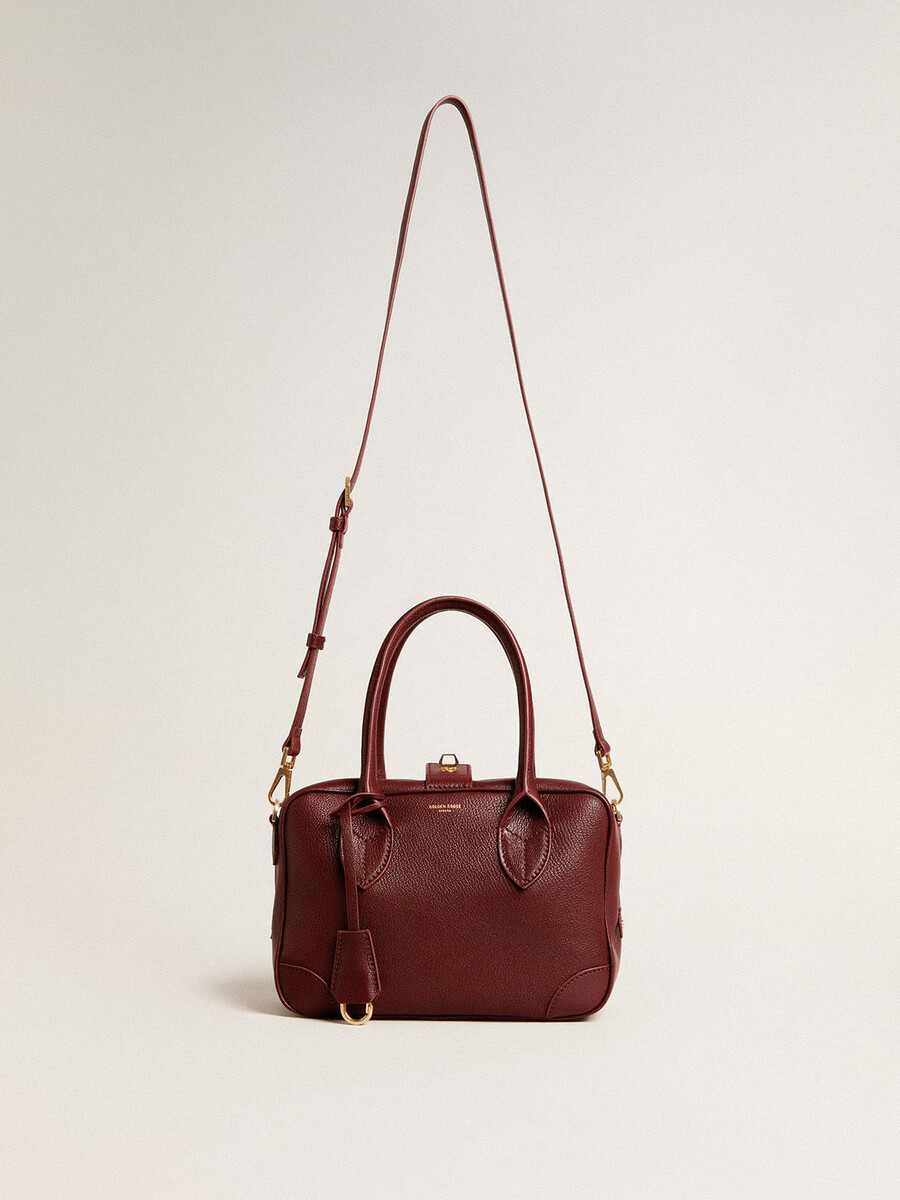 vita-tasche aus burgunderrotem leder mit goldenen details
