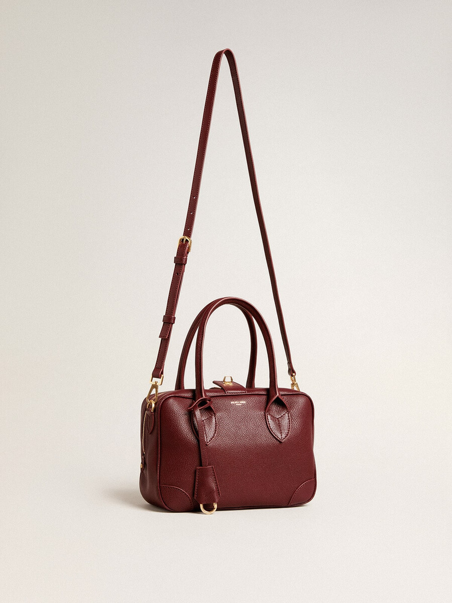 vita-tasche aus burgunderrotem leder mit goldenen details
