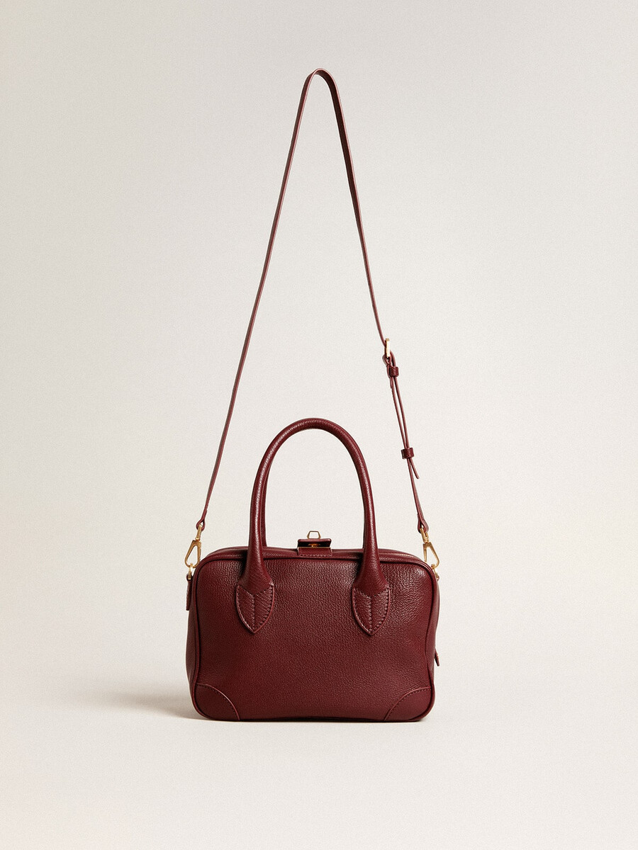 vita-tasche aus burgunderrotem leder mit goldenen details