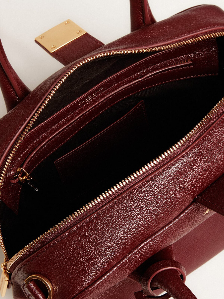 vita-tasche aus burgunderrotem leder mit goldenen details